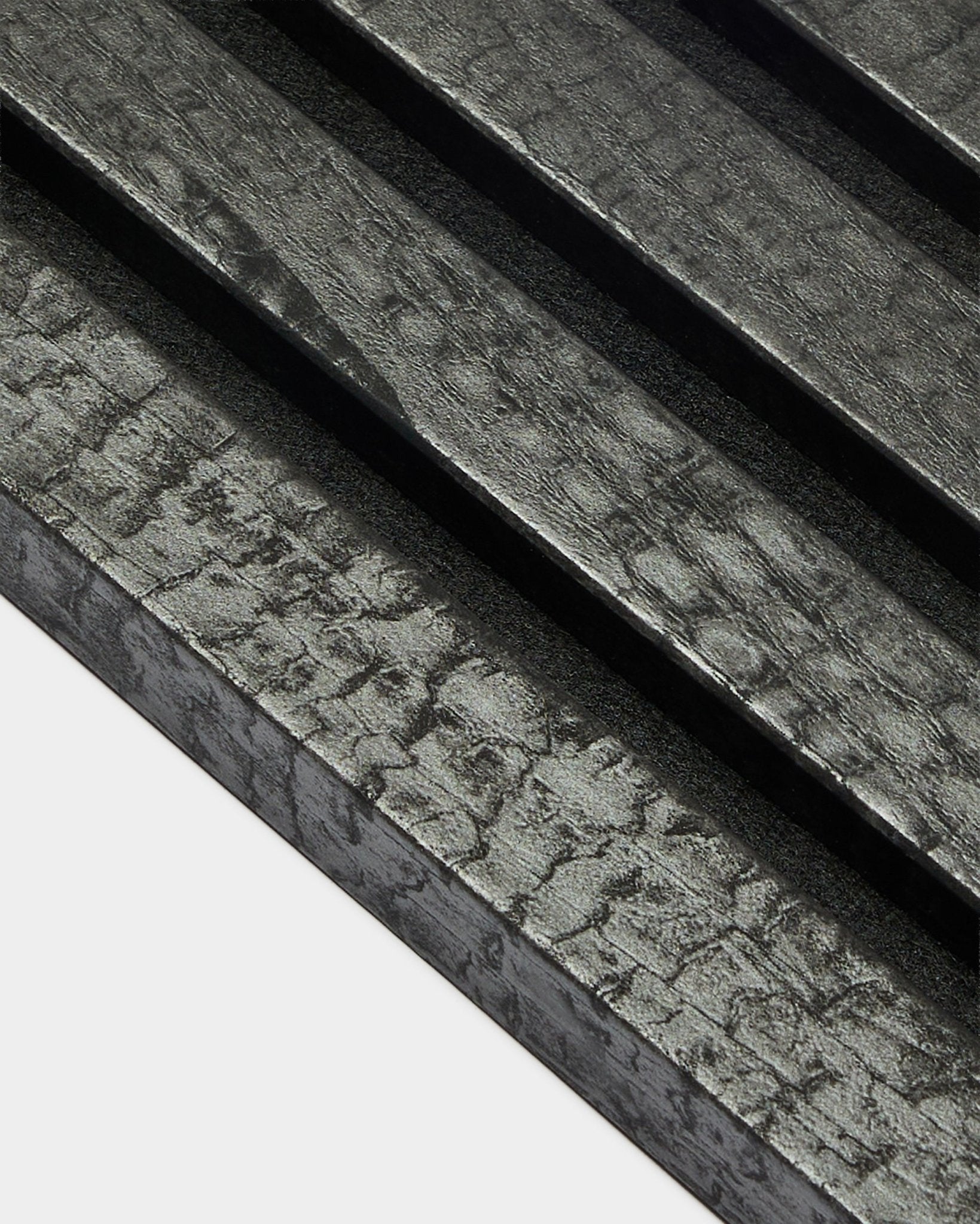 WoodUpp Akupanel End Lamella in Charcoal (2.2 cm), featuring diagonal, textured acoustic wood panels with a charred black finish for wall installation.