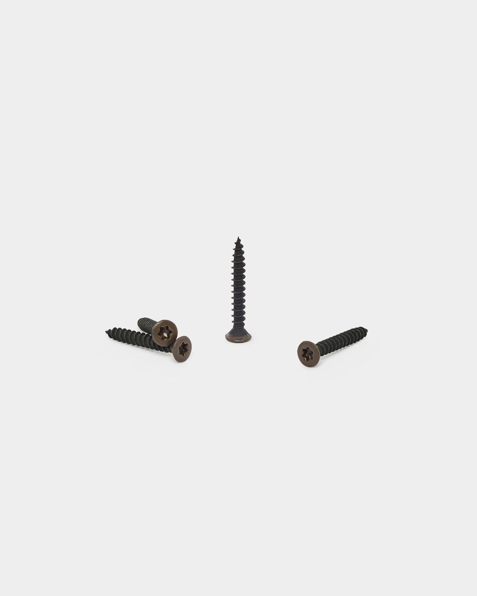 Three bronzed brown WoodUpp screws, one upright and two lying down, designed for attaching felt backing to Akupanel acoustic panels. Pack of 100.