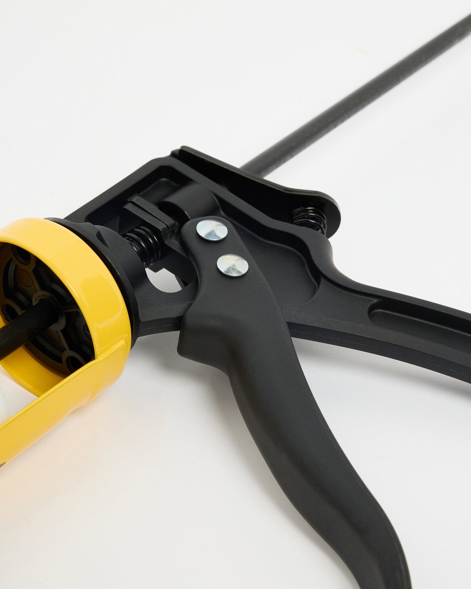 Close-up of the WoodUpp black and yellow grout gun (290 ml), a CREATE accessory for Akupanel acoustic panel installation, displayed on a white surface.