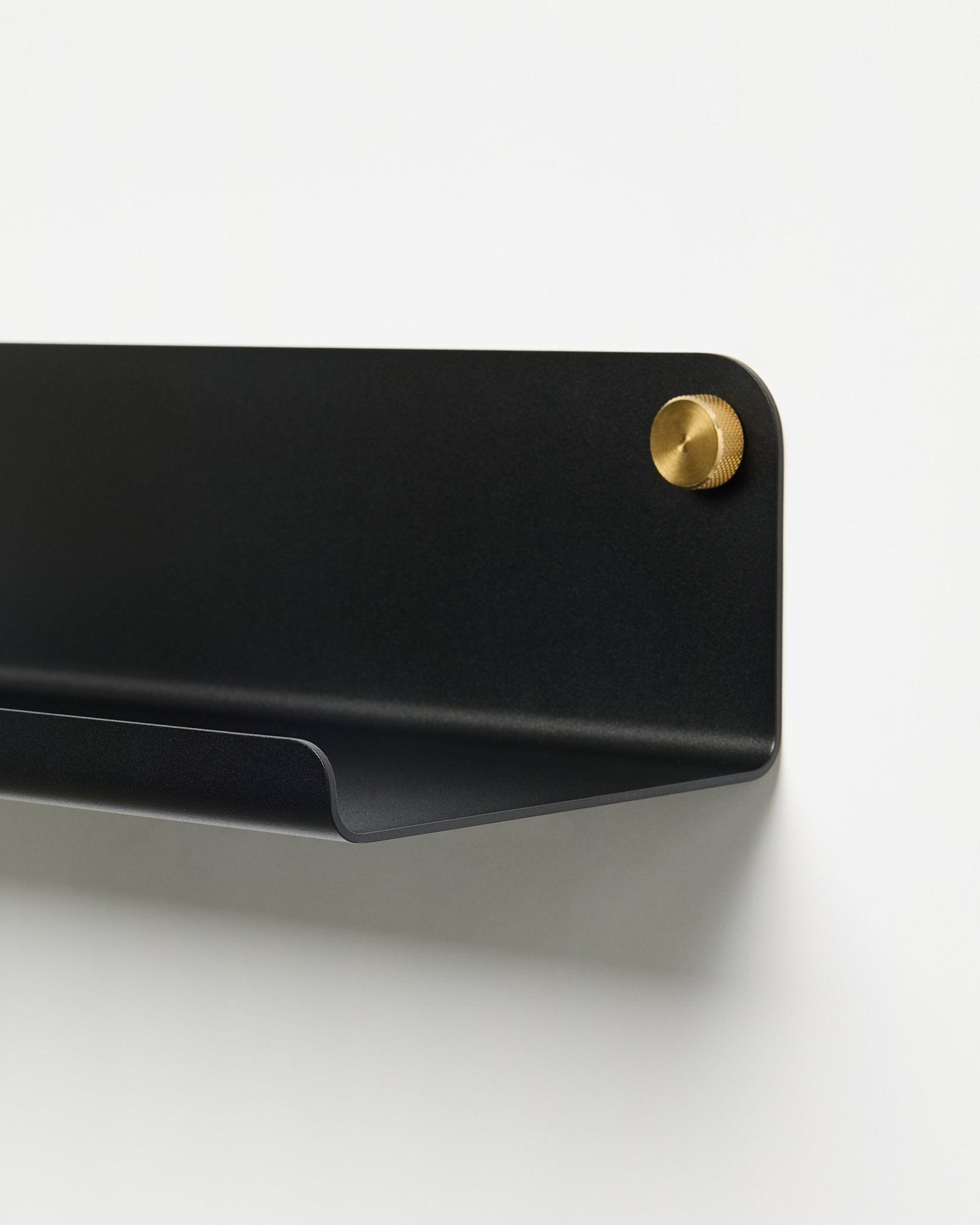 Close-up of the WoodUpp Norr Wide Shelf (51.9 cm) accessory in powder-coated black metal with gold screw, placed against a plain white background.