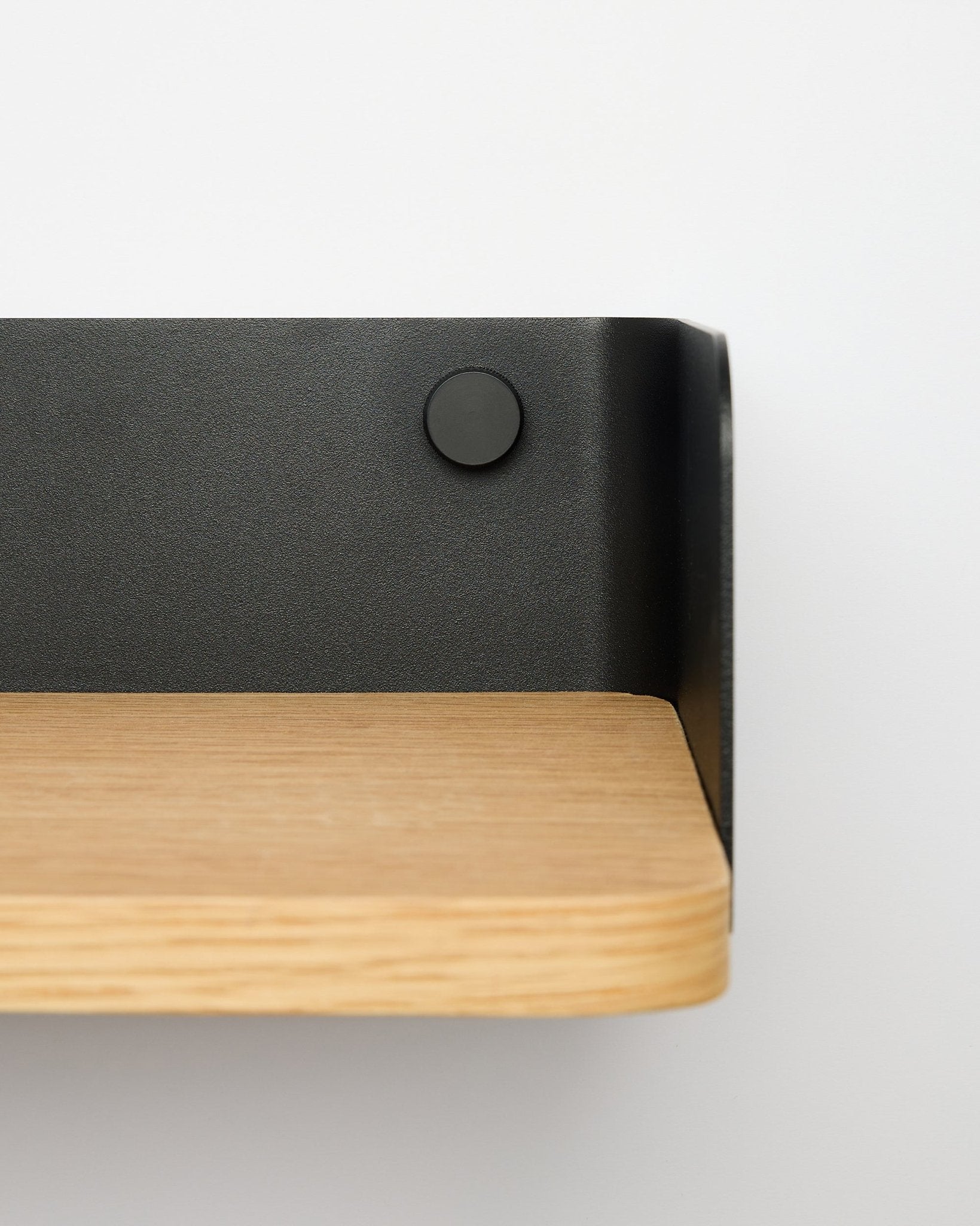 Linn Bookshelf by WoodUpp in natural oak, 55.9 cm wide, with black metal bracket, mounted on a white wall; close-up view from the right side.