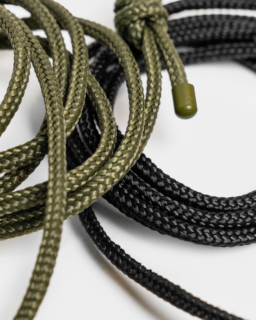 Vindar | Gallery String by WoodUpp: braided green and black string with plastic tips, displayed next to a photo hanging string on a white background.