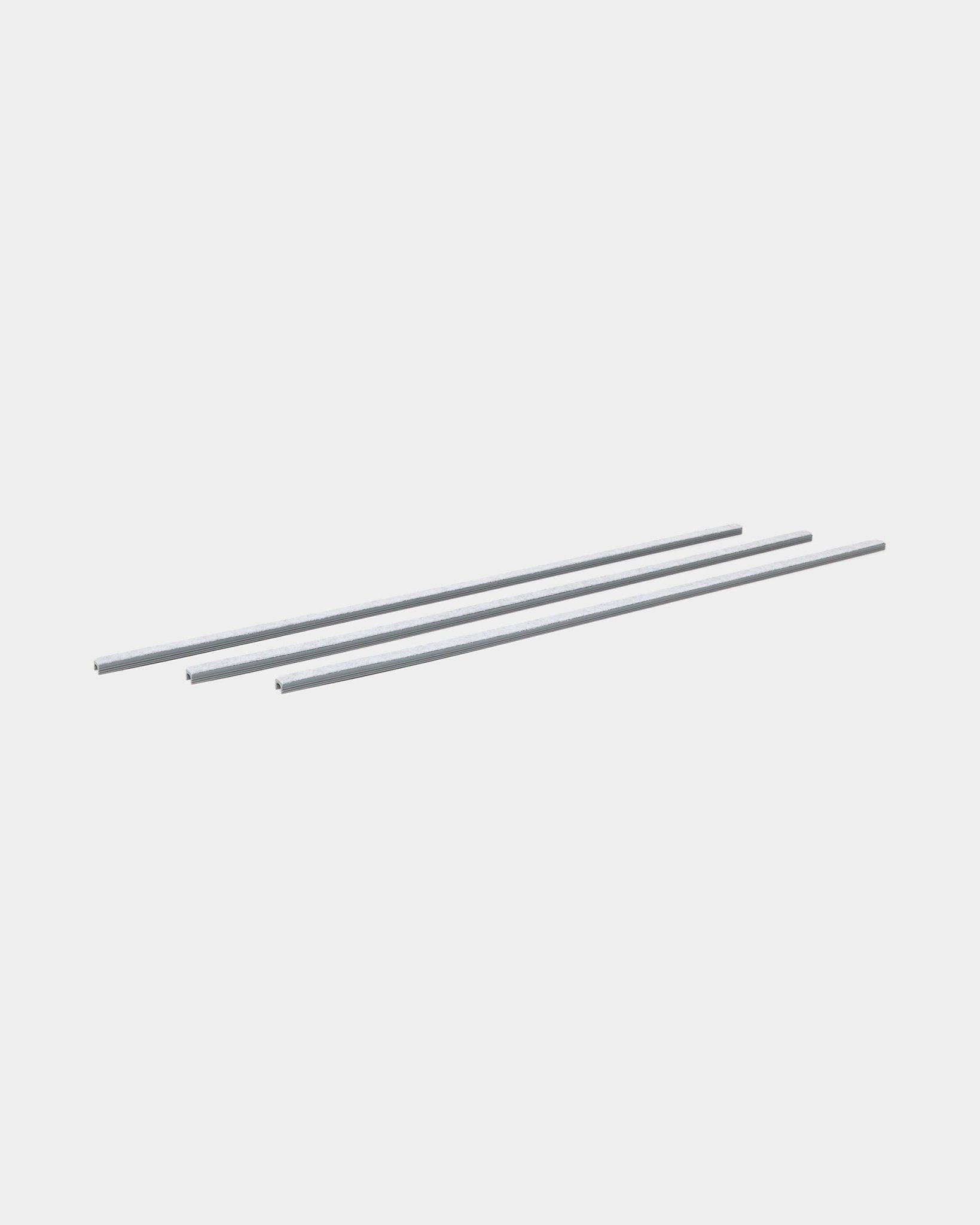 Three grey Dupps Pop-on Cable Covers (3 pcs) by WoodUpp are lined up parallel, designed for organizing cables with Akupanel acoustic wood panels.