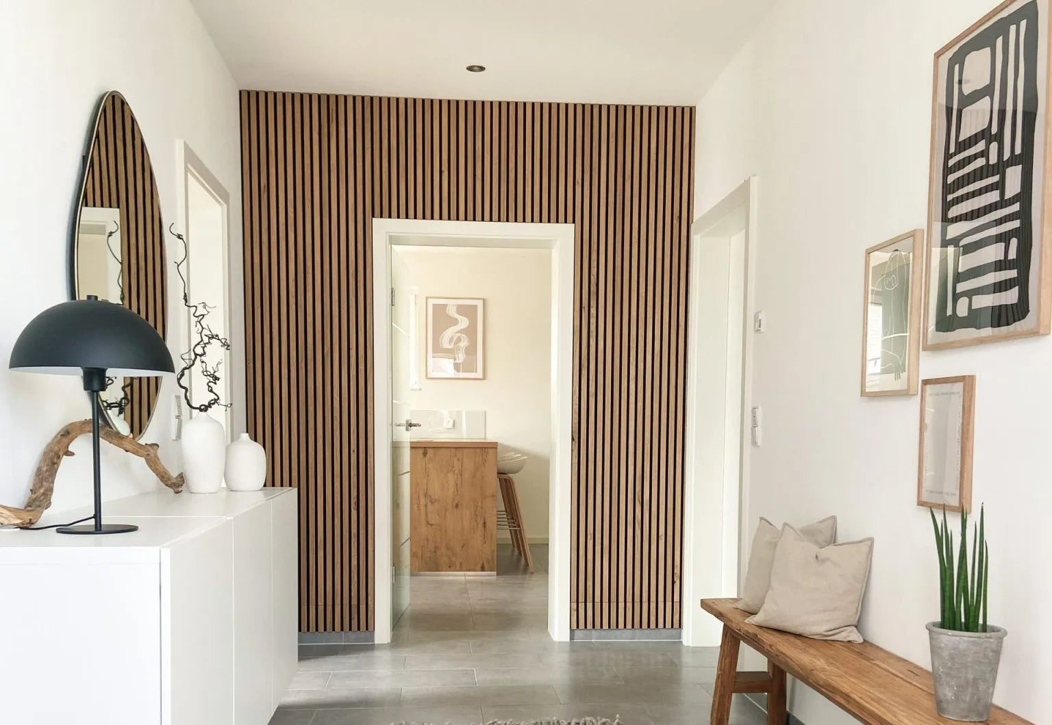 A modern hallway with a Nordic Akupanel wood slat acoustic accent wall, white walls, a cushioned bench, and minimalist decor.