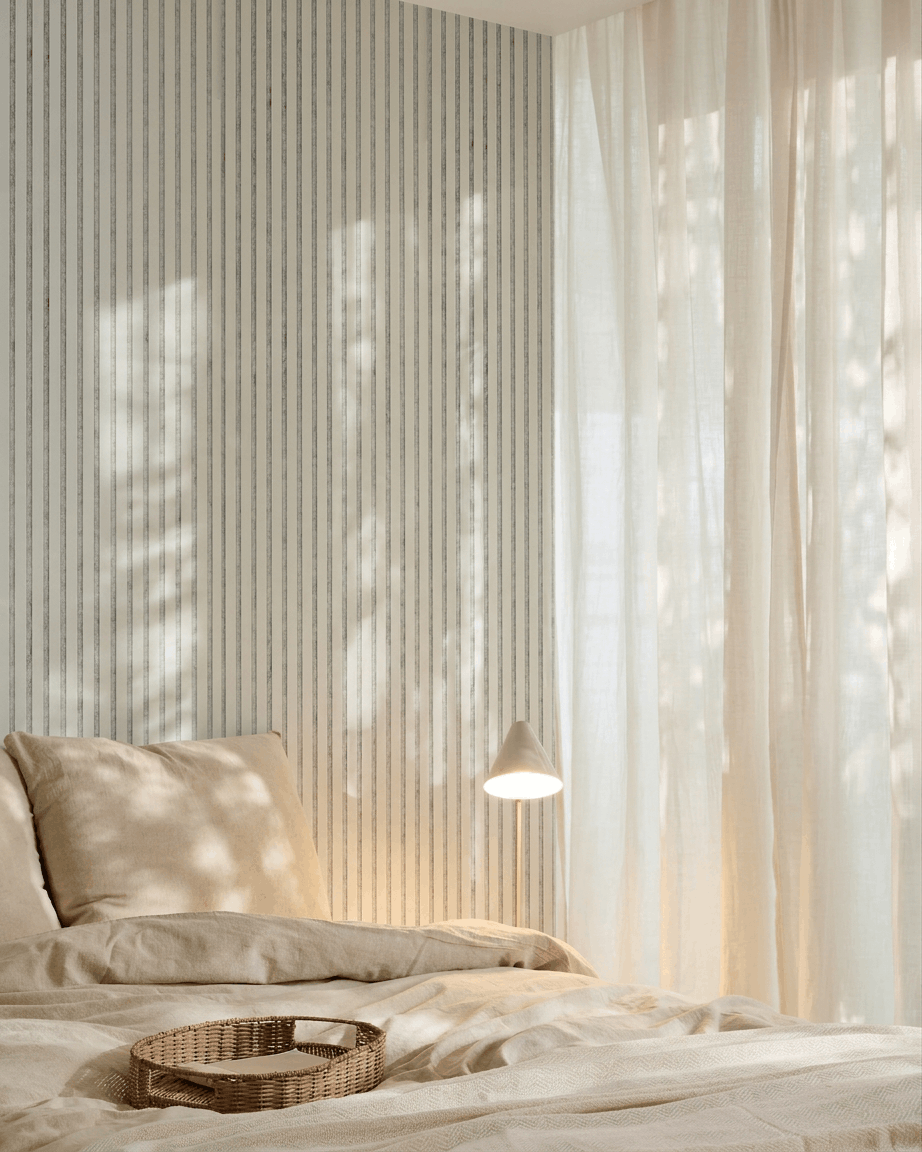 Minimalist bedroom featuring beige bedding, a wicker tray, striped wallpaper, and a WoodUpp Akupanel acoustic wood panel in Snow Grey Felt for sound absorption.