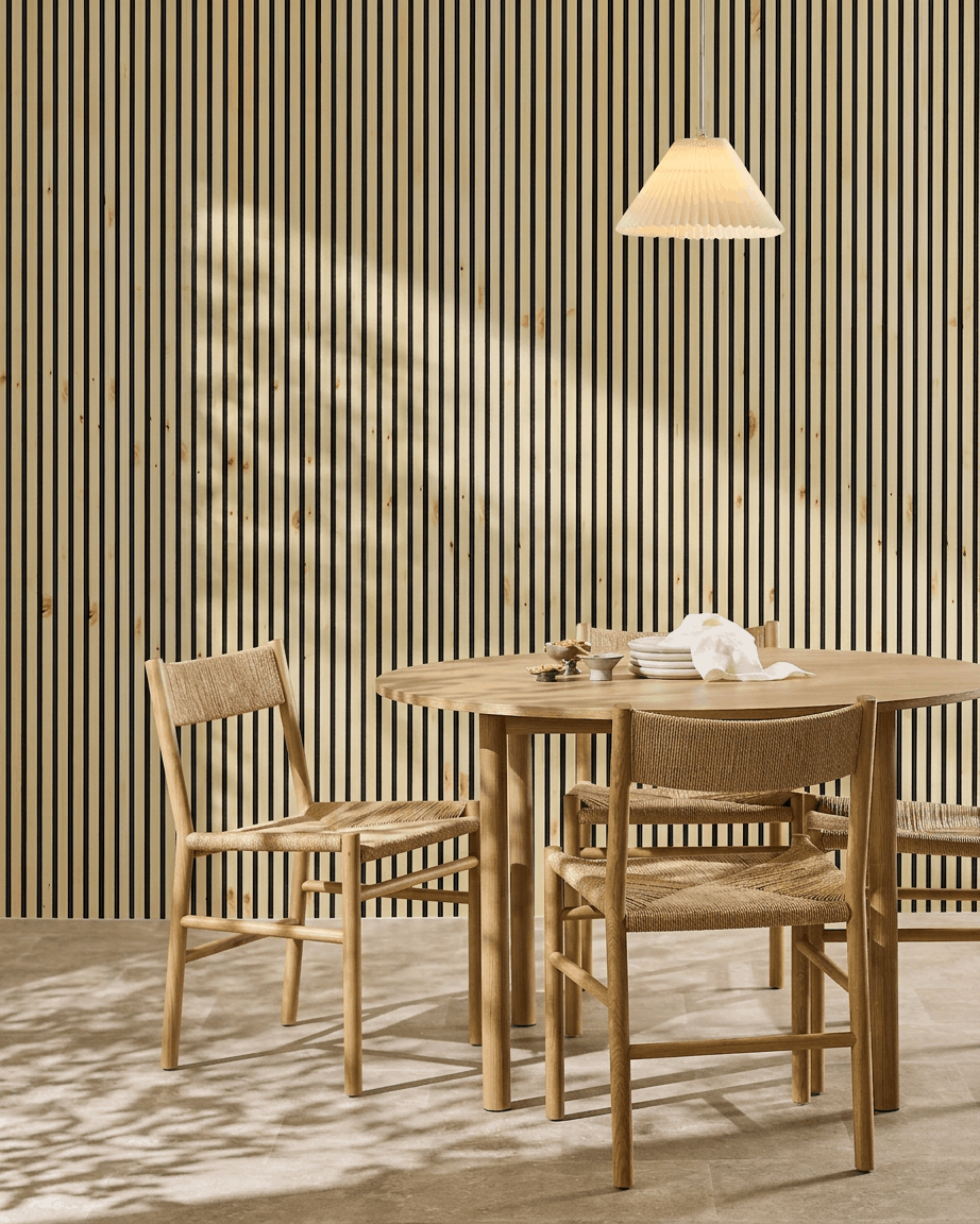 WoodUpp Akupanel acoustic panel in natural wood, alp, and black felt adds a warm, minimalist Nordic touch to a Scandinavian dining area with table and chairs.